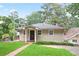 Quaint home with a brick walkway leading to the front door and a well-maintained lawn surrounded by mature trees at 6381 Lakeview Dr, Buford, GA 30518