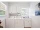 Functional laundry room with washer, dryer, sink, and ample storage in white cabinets, enhanced by natural light at 6381 Lakeview Dr, Buford, GA 30518
