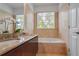 Bright bathroom featuring a double granite vanity, tiled walls, and a soaking tub with a window at 200 Renaissance Ne Pkwy # 219, Atlanta, GA 30308