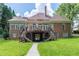 Backyard view of a brick home with a raised deck, outdoor stairs, and a spacious lawn, perfect for entertaining at 5435 Chelsen Wood Dr, Duluth, GA 30097