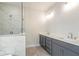 Bright bathroom featuring dual sinks, gray cabinetry, and glass enclosed shower at 148 Palm St, Holly Springs, GA 30115