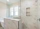 Corner view of marble-tiled shower with built-in shelving and glass enclosure at 148 Palm St, Holly Springs, GA 30115