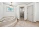 Bright bathroom features a large soaking tub, elegant chandelier, and a separate glass-enclosed shower at 2065 Innsfail Dr, Snellville, GA 30078