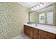 A well lit half bathroom with floral wallpaper and a large mirror at 2065 Innsfail Dr, Snellville, GA 30078
