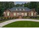 Beautiful single-story brick home with manicured lawn and inviting circular driveway and lush landscaping at 2065 Innsfail Dr, Snellville, GA 30078