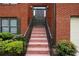 Close-up of the front door with brick steps and a black railing, surrounded by manicured landscaping at 655 Golden Meadows Ln, Suwanee, GA 30024