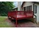 Red wooden deck with sturdy railings offers an entertainment space with a view of the green landscape at 655 Golden Meadows Ln, Suwanee, GA 30024