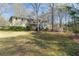 Spacious backyard with a lush lawn, mature trees, and a view of the home's exterior and screened-in porch at 115 Flagstop Run, Fayetteville, GA 30215