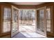 View from indoors through open french doors to an outdoor wood deck and natural backyard at 115 Flagstop Run, Fayetteville, GA 30215