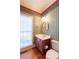 Cozy half bath with red vanity, oval mirror and decorative striped wallpaper at 115 Flagstop Run, Fayetteville, GA 30215
