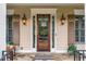 Close up of front door featuring stone flooring, sconce lighting and a stained wood front door with glass panes at 2403 Wistful Way, Marietta, GA 30066