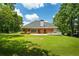 Lush backyard view of brick home, showcasing a patio, mature trees, and green lawn, ideal for outdoor enjoyment at 40 Costleys Bridge Dr, Oxford, GA 30054