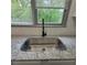 Granite countertops surround a stainless steel kitchen sink, under a bright window, perfect for prepping gourmet meals at 3045 Binghampton Ln, Lawrenceville, GA 30044