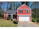 Charming red two-story home with a well-manicured lawn and two-car garage at 7472 Woods Ct, Lithonia, GA 30058