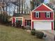 Charming two-story home featuring a red exterior, black shutters, and a well-manicured front yard at 7472 Woods Ct, Lithonia, GA 30058