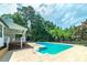 Outdoor pool area surrounded by a concrete deck and lush greenery with white porch in the background at 858 Pates Creek Rd, Stockbridge, GA 30281