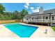 In-ground swimming pool surrounded by lush trees and manicured lawn, along with a covered deck at 858 Pates Creek Rd, Stockbridge, GA 30281