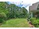 View of a well-maintained backyard with a large grassy area, mature trees, and colorful flower beds at 825 Chalet Hls, Mcdonough, GA 30253