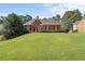 Charming red brick home with a manicured lawn, black shutters, and lush landscaping at 5831 Wembley Dr, Douglasville, GA 30135