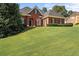 Charming single-story brick home featuring a lush green lawn, manicured shrubs, and inviting curb appeal at 5831 Wembley Dr, Douglasville, GA 30135