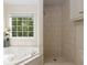 Bathroom featuring a soaking tub, a tiled shower, and natural light at 6280 Autry Mill Rd, Cumming, GA 30028
