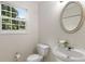 A half bath featuring a pedestal sink, an oval mirror, and a window at 6280 Autry Mill Rd, Cumming, GA 30028