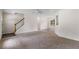 Spacious living room with neutral carpeting, staircase, and view into dining area at 6280 Autry Mill Rd, Cumming, GA 30028