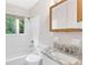 Bathroom featuring tiled shower, granite countertops, sink, mirror, toilet and window at 6671 Gano Dr, Riverdale, GA 30274
