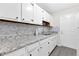 Galley kitchen featuring white cabinets, granite countertops, tile backsplash and stainless steel faucet at 6671 Gano Dr, Riverdale, GA 30274