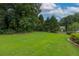 Spacious backyard with a well-manicured lawn, mature trees, and a wooden fence at 388 Rose Creek Pl, Woodstock, GA 30189