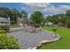 Scenic backyard featuring rock landscaping around a fire pit area with seating, and green grass at 388 Rose Creek Pl, Woodstock, GA 30189