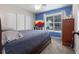 Bright bedroom with blue accent wall, large windows, and closet doors at 388 Rose Creek Pl, Woodstock, GA 30189