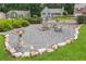Cozy backyard firepit area with gravel, stone border, mature landscaping, and seating, perfect for outdoor gatherings at 388 Rose Creek Pl, Woodstock, GA 30189