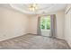 Spacious bedroom with a tray ceiling, neutral carpet, and a view of the outdoors at 3255 Marine Rd, Cumming, GA 30041