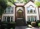 Inviting home entrance with stone steps, a decorative wreath, and manicured hedges leading to an arched doorway at 5820 Elm Tree Dr, Buford, GA 30518