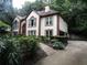 Two-story home with white siding, brown trim, lush landscaping, and a side-entry garage, nestled in a wooded area at 5820 Elm Tree Dr, Buford, GA 30518