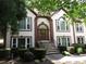 Exterior view of home featuring arched entryway, manicured shrubs, stone steps and lush foliage at 5820 Elm Tree Dr, Buford, GA 30518