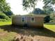 View of the back of the brick house with small yard and green grass surrounded by trees at 2369 Christian Cir, Covington, GA 30016