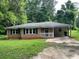 Single-story brick home with black shutters and covered parking surrounded by mature trees at 2369 Christian Cir, Covington, GA 30016