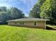 Back of ranch-style house with an expansive green lawn surrounded by mature trees in a serene setting at 2369 Christian Cir, Covington, GA 30016