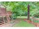View of a lush backyard with a deck and wooden stairs leading to the upper level of the house at 2291 Smokehouse Path, Lawrenceville, GA 30044