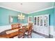 Charming dining room features a statement chandelier, turquoise walls, and beautiful hardwood floors at 4365 Mantle Ridge Dr, Cumming, GA 30041