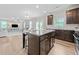 Bright, open-concept kitchen with dark wood cabinets, island seating, and view into the living room with fireplace at 432 Providence Walk St, Canton, GA 30114