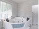 Features a luxurious tub, a window with blinds, and a glass-enclosed shower at 4408 Shiloh Trl, Powder Springs, GA 30127