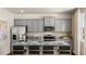 A bright kitchen boasts gray cabinetry, granite countertops, stainless appliances, an island with seating, and natural light from a window at 1622 Palladian Way, Lithonia, GA 30058
