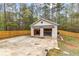A detached, two-car garage features a concrete driveway, with partial fencing, and surrounded by dense trees at 195 Blackberry Run, Fayetteville, GA 30214