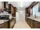 Galley kitchen featuring dark wood cabinetry, granite counters, and stainless steel appliances at 314 Spring Falls Drive, Lawrenceville, GA 30045