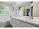 Bright bathroom featuring a bathtub, double sink vanity, and wallpaper with decorative vines at 3770 Wake Robin Way, Cumming, GA 30028