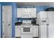 Kitchen featuring white appliances and cabinetry against blue walls, with a white door at 3770 Wake Robin Way, Cumming, GA 30028