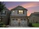 Charming townhome featuring a stone facade and two-car garage with decorative doors against a twilight sky at 252 Stone Park Dr, Woodstock, GA 30188